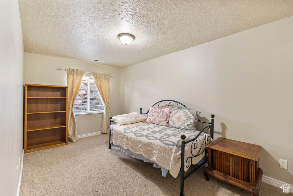 Carpeted bedroom with baseboards, a textured ceiling, and visible vents