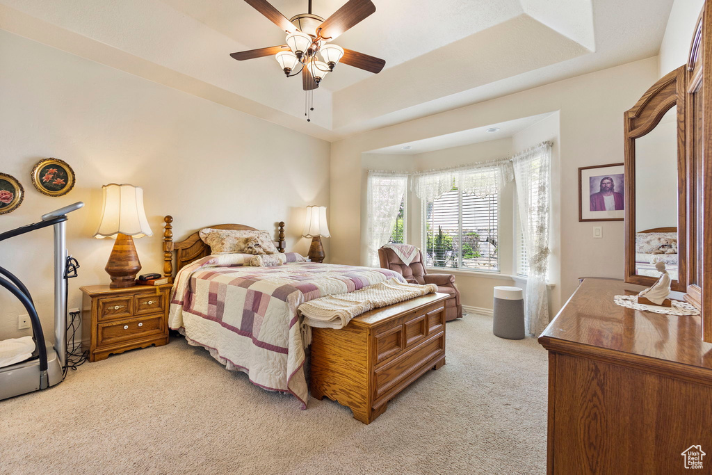 Bedroom featuring light colored carpet, a ceiling fan, and a raised ceiling