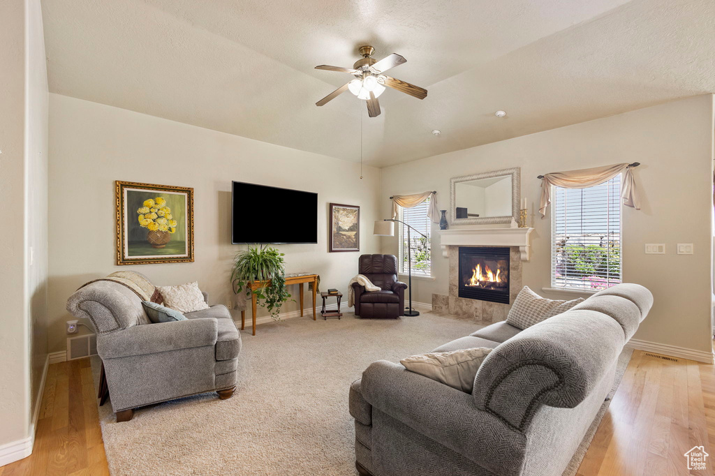 Living area featuring a high end fireplace, baseboards, ceiling fan, and light wood finished floors