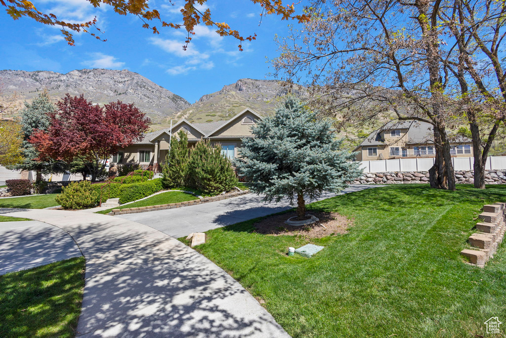 View of front facade featuring a front lawn, a mountain view, and fence