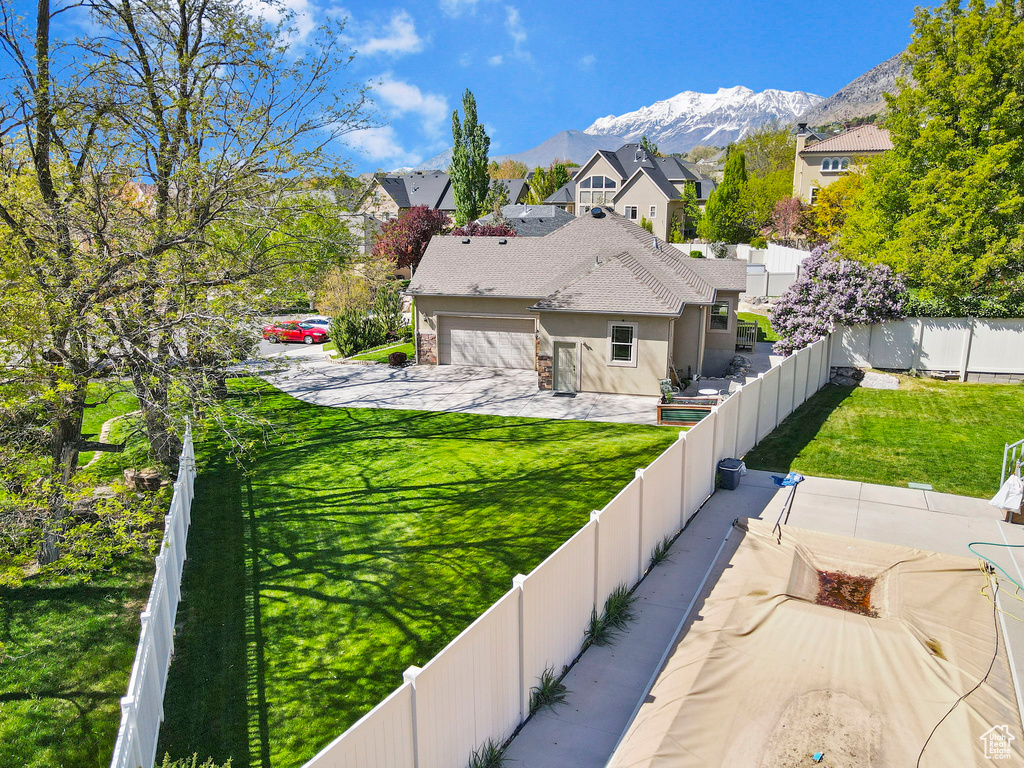 Exterior space with a residential view, a garage, stucco siding, a fenced backyard, and a mountain view