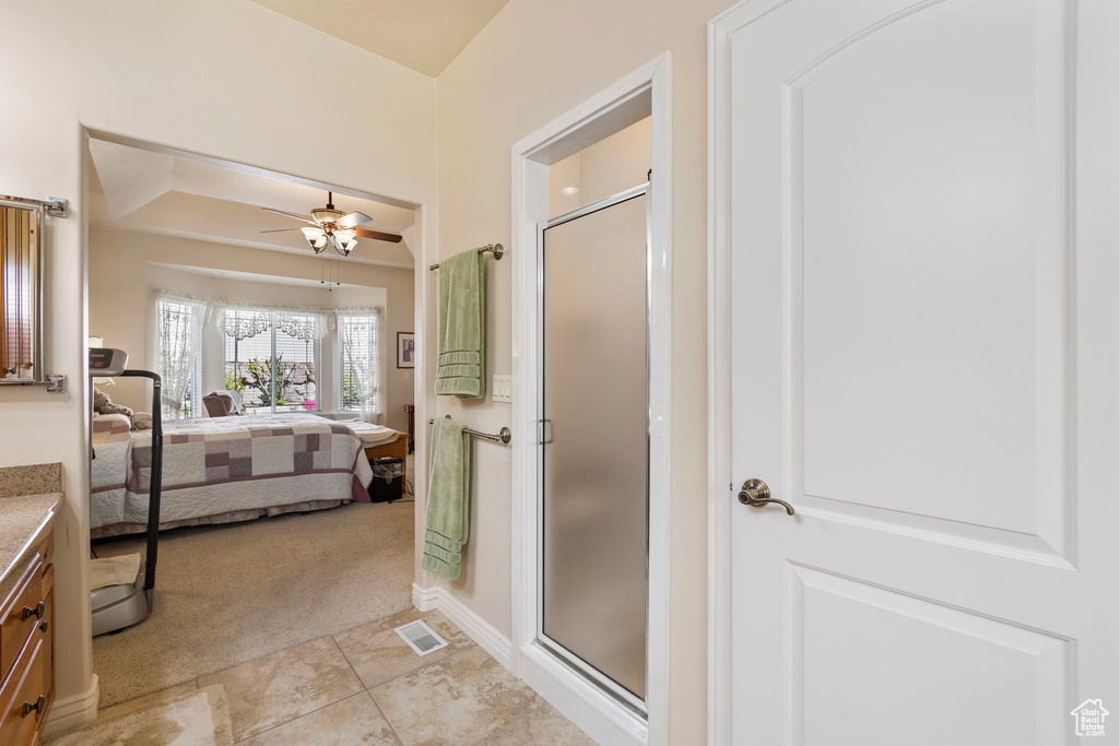 Bathroom featuring a ceiling fan, visible vents, a shower stall, vanity, and ensuite bath