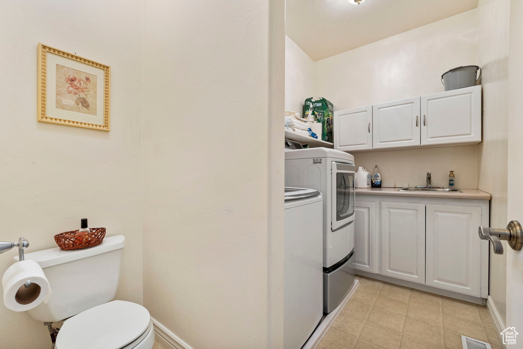 Laundry room featuring a sink, light tile patterned floors, washing machine and dryer, and visible vents