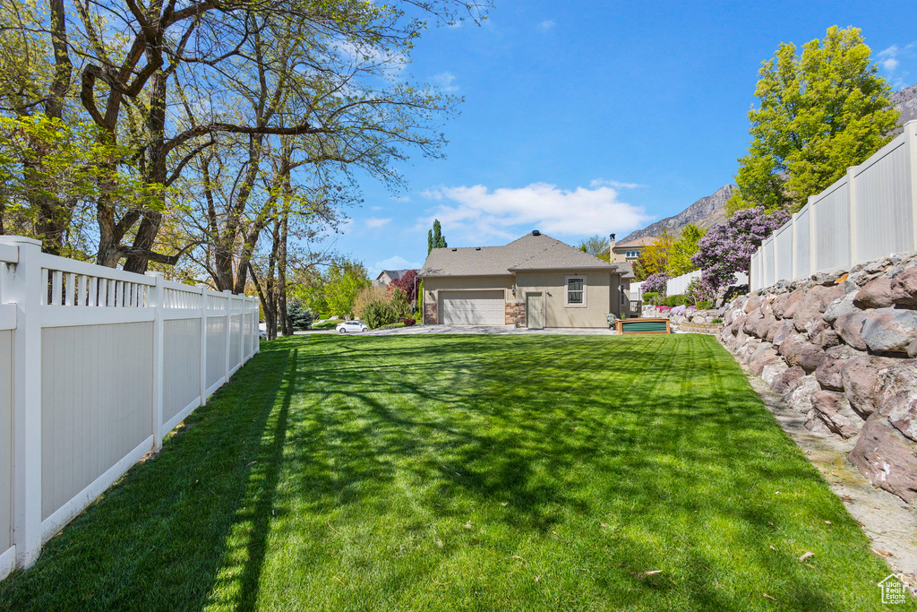 View of yard with an attached garage and a fenced backyard