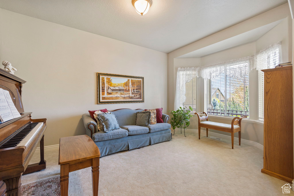 Living area with baseboards and light carpet