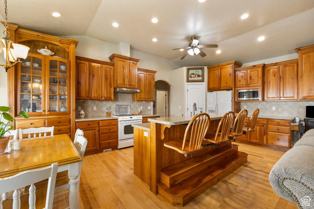 Kitchen with decorative backsplash, under cabinet range hood, white appliances, and ceiling fan