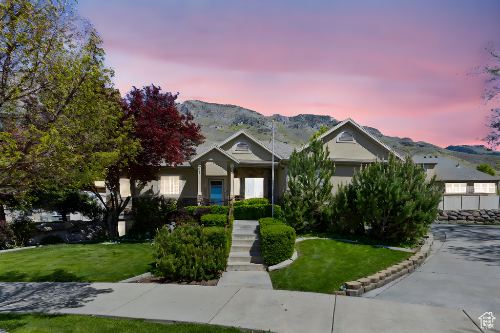 View of front facade featuring a mountain view, stucco siding, and a front yard