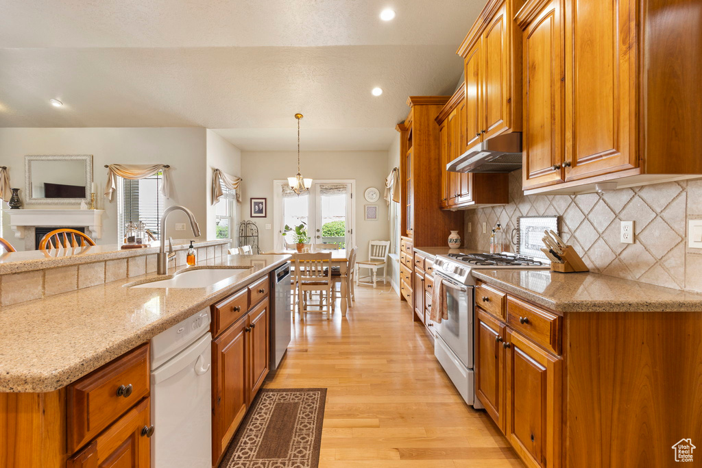 Kitchen with stainless steel dishwasher, a sink, brown cabinetry, and gas stove