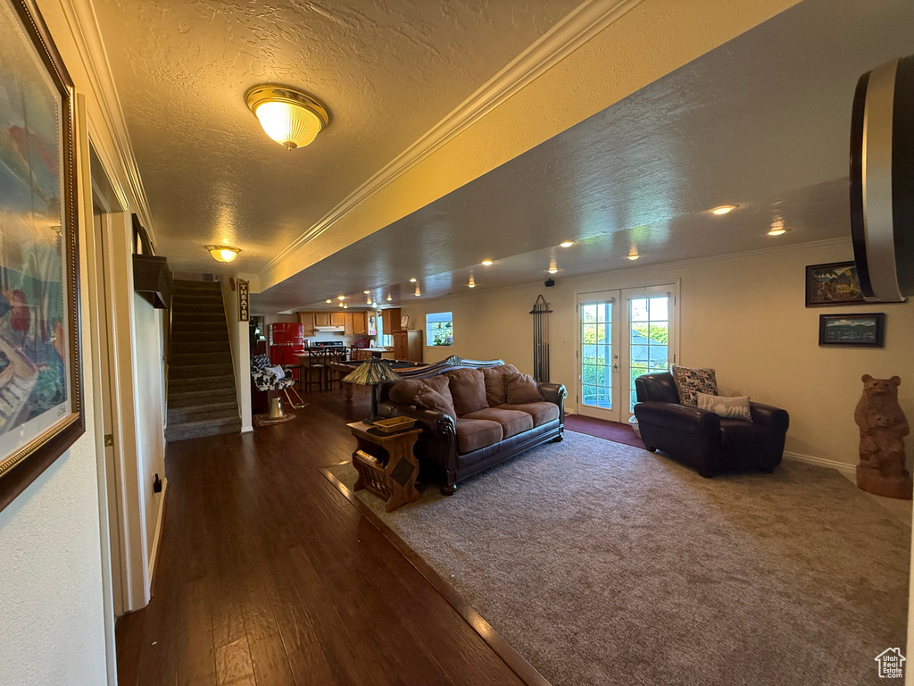 Living area featuring ornamental molding, stairs, dark wood-type flooring, a textured ceiling, and baseboards