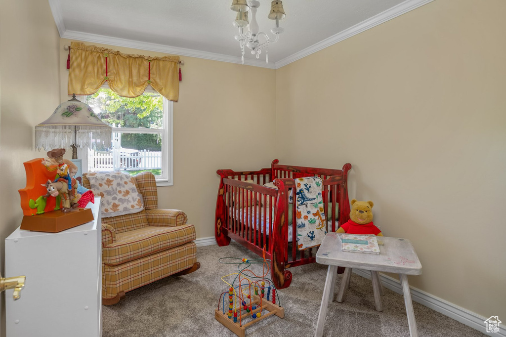 Carpeted bedroom with ornamental molding, baseboards, and a chandelier