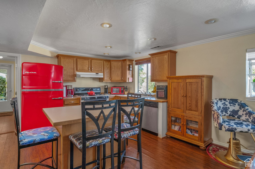 Kitchen featuring gas range, under cabinet range hood, dishwasher, fridge, and wood finished floors