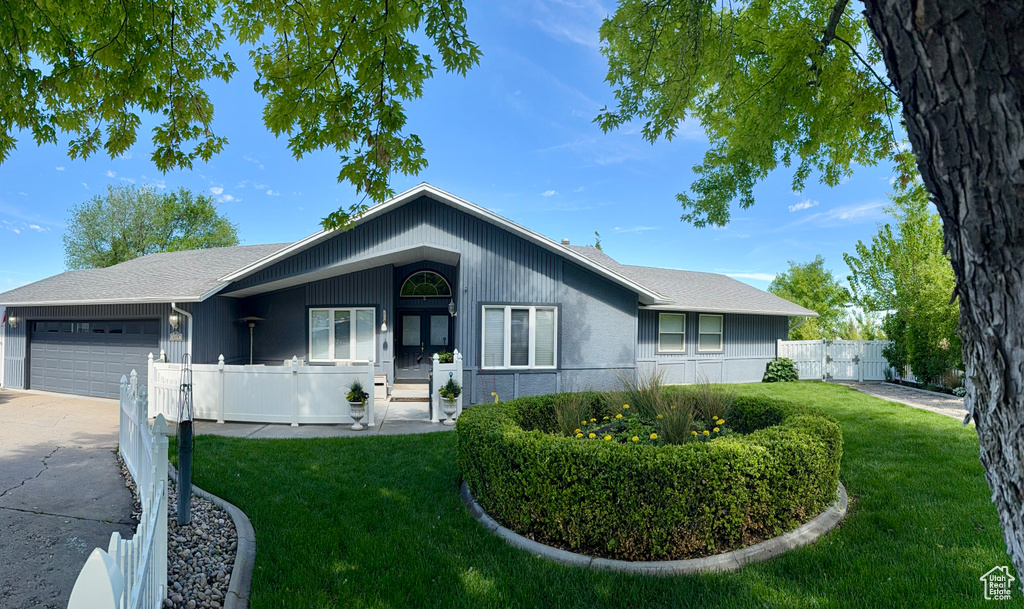 Ranch-style house featuring an attached garage, driveway, and french doors