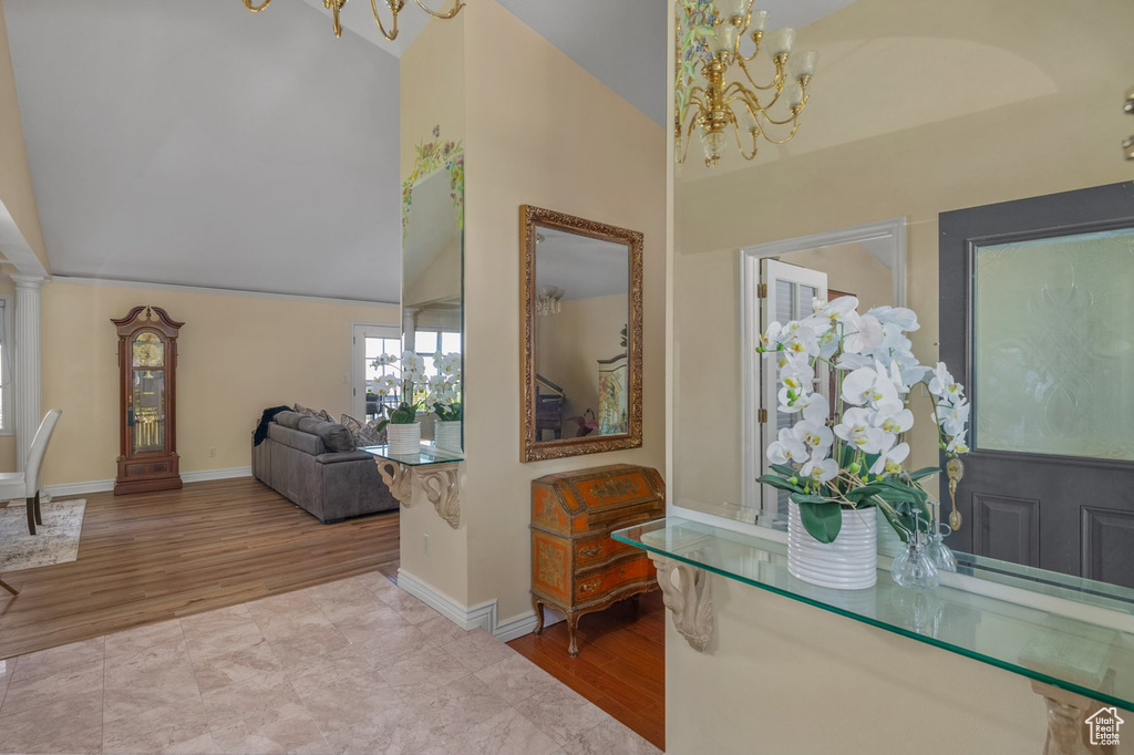 Foyer entrance with a chandelier, high vaulted ceiling, wood finished floors, and baseboards