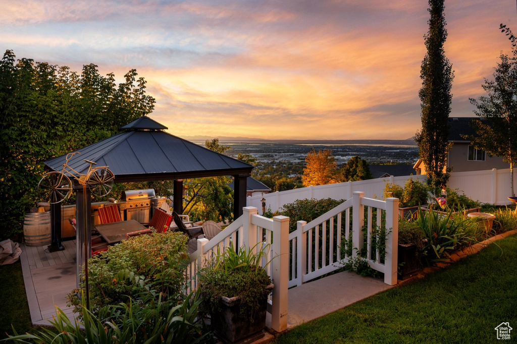 Patio terrace at dusk featuring a gazebo, fence, and area for grilling