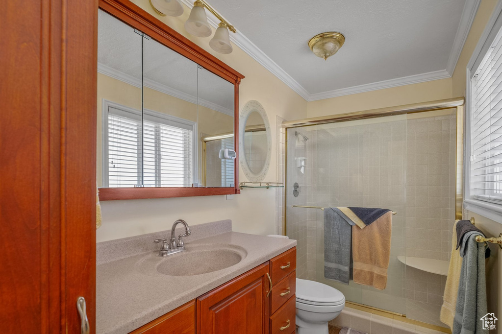 Full bath with a shower stall, vanity, ornamental molding, and toilet