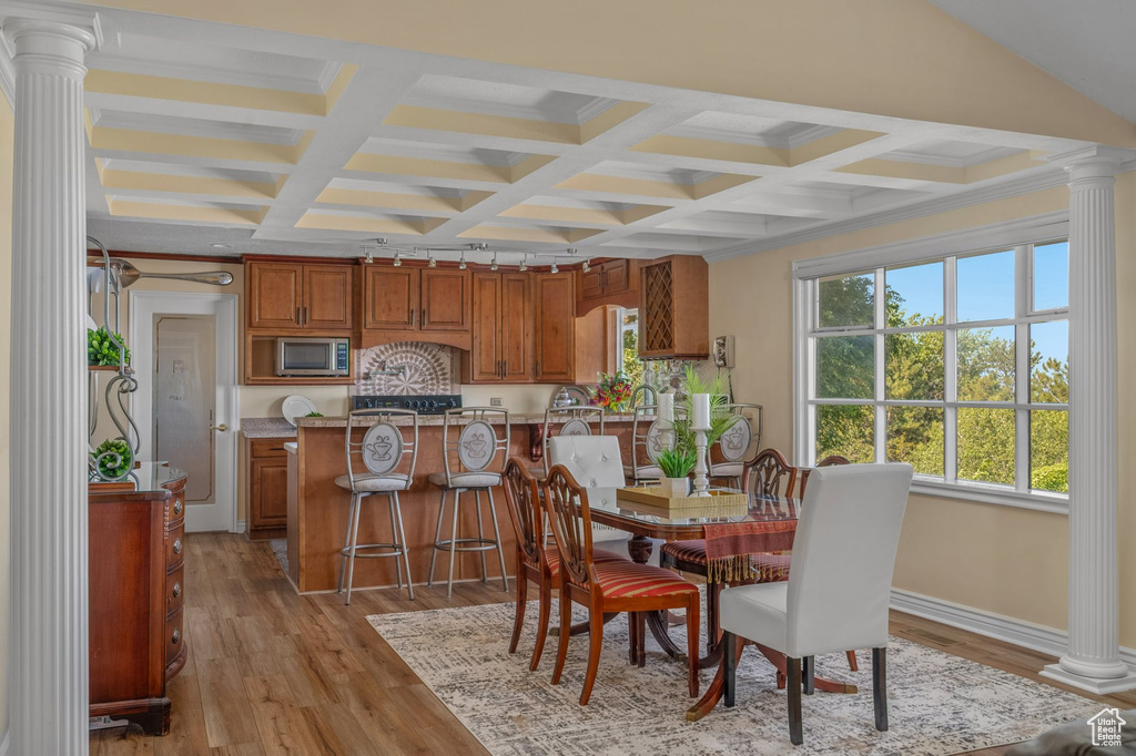 Dining area with ornate columns, coffered ceiling, light wood-style flooring, beamed ceiling, and baseboards