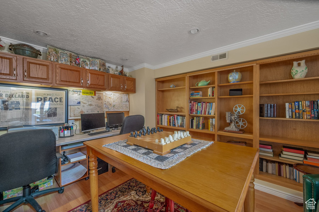 Office featuring light wood-style floors, crown molding, and a textured ceiling