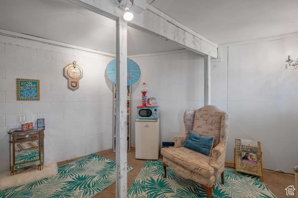 Living area featuring concrete block wall and carpet flooring