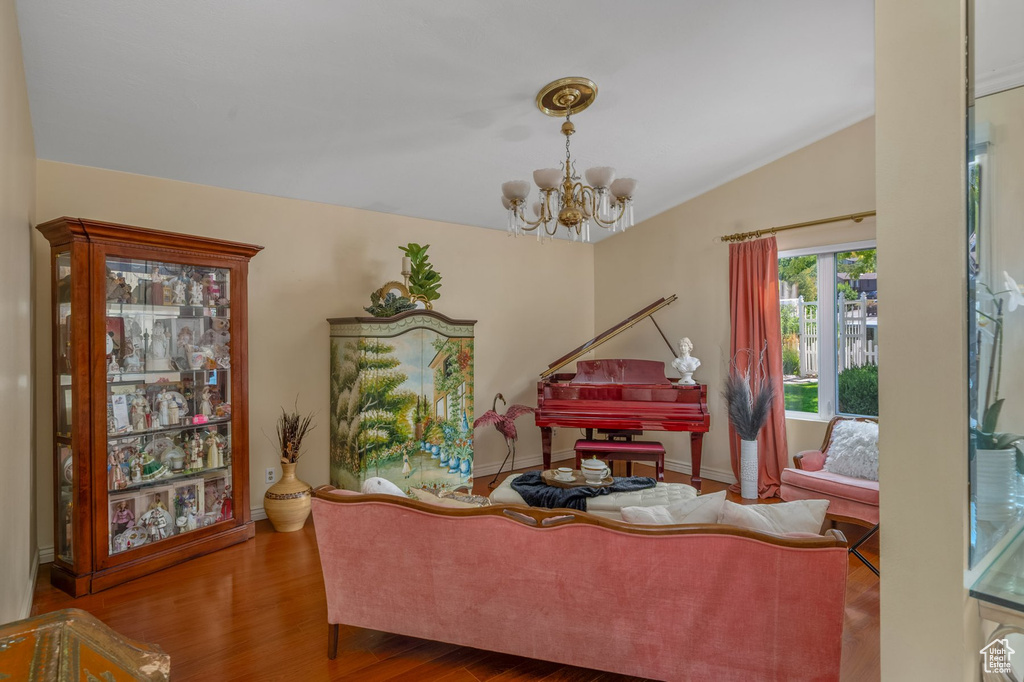 Sitting room with a chandelier, vaulted ceiling, wood finished floors, and baseboards