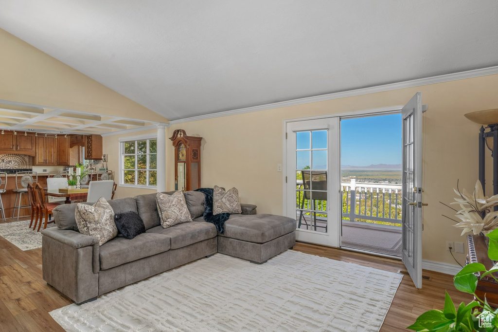 Living room with light wood-style flooring, ornamental molding, lofted ceiling, and baseboards