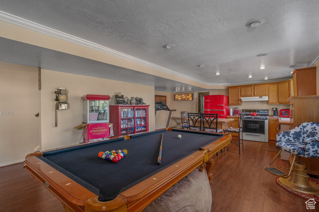 Recreation room with wood finished floors, billiards, a textured ceiling, ornamental molding, and baseboards