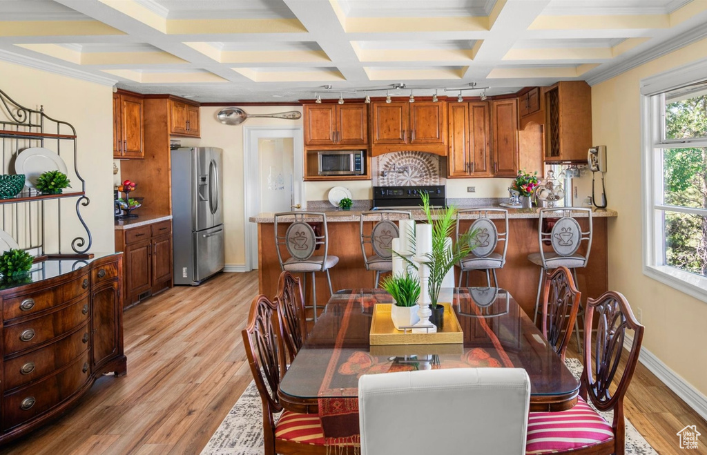 Dining space featuring coffered ceiling, light wood-type flooring, baseboards, beamed ceiling, and crown molding