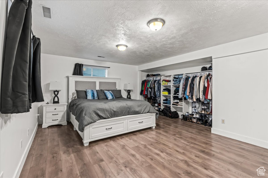 Bedroom featuring a textured ceiling, wood finished floors, and baseboards