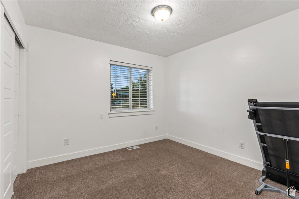 Unfurnished bedroom featuring a textured ceiling, carpet flooring, baseboards, and a closet