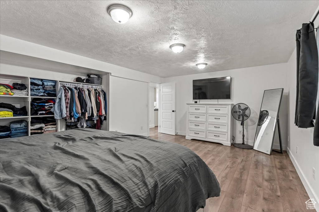 Bedroom featuring baseboards, a textured ceiling, and wood finished floors