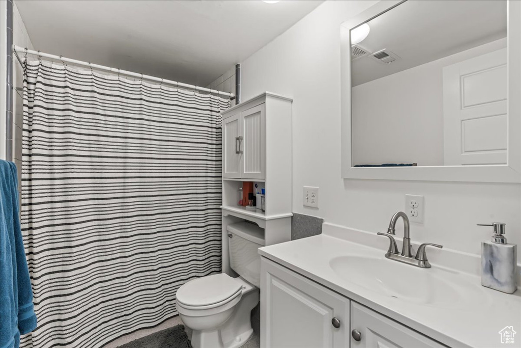 Bathroom with vanity, toilet, and curtained shower
