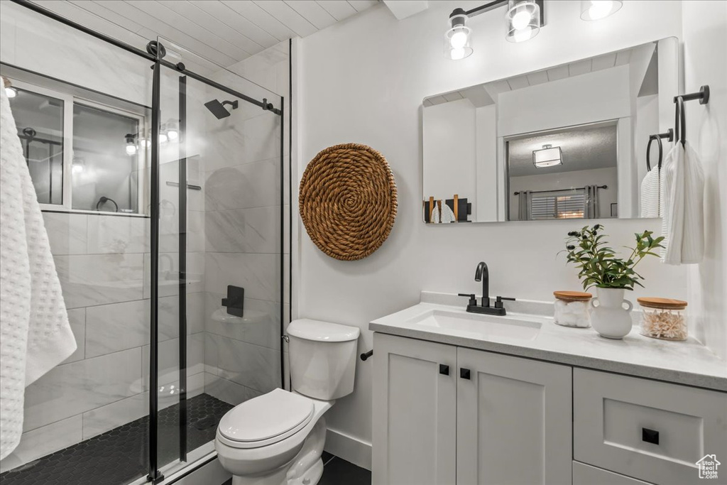 Full bath featuring toilet, a shower stall, vanity, and baseboards