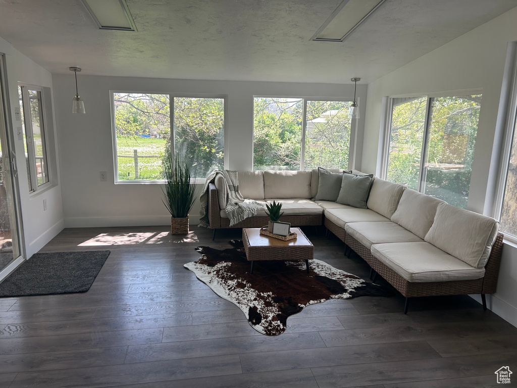 Sunroom / solarium featuring vaulted ceiling, wood-type flooring, baseboards, and a wooden deck