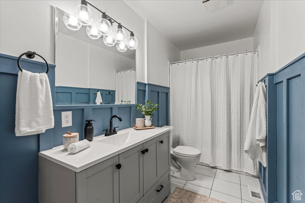 Bathroom featuring toilet, tile patterned flooring, wainscoting, vanity, and a shower with shower curtain