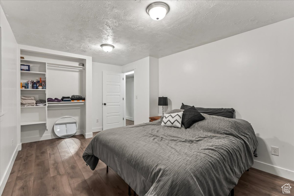 Bedroom featuring baseboards, wood finished floors, a textured ceiling, and a closet