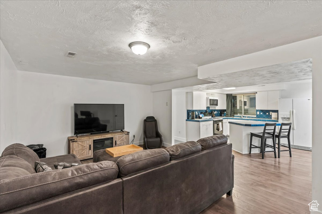 Living area featuring light wood-style flooring and a textured ceiling