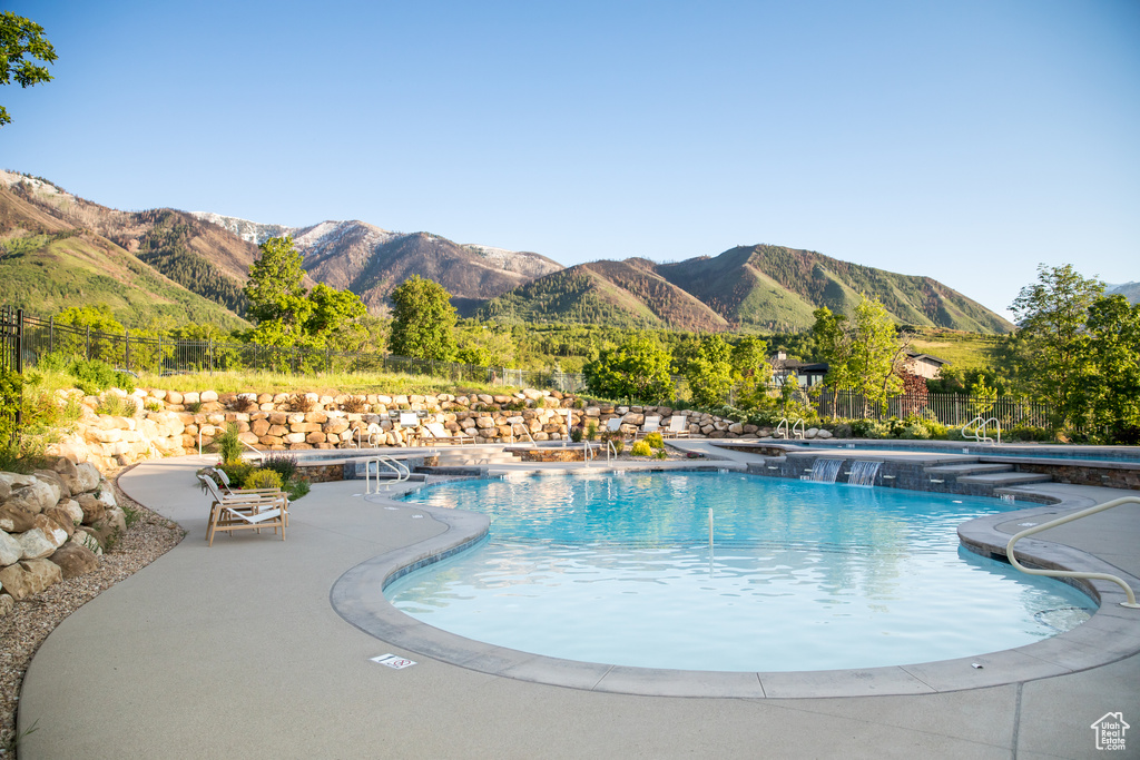 Community pool featuring a mountain view, fence, and a patio area