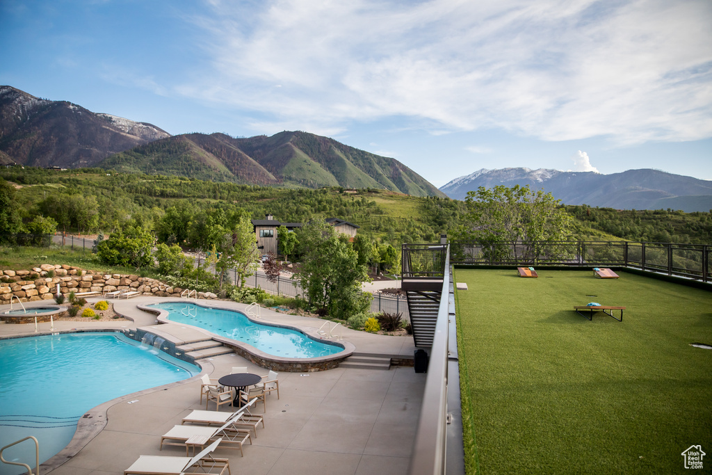 Community pool with a mountain view, fence, and a patio area