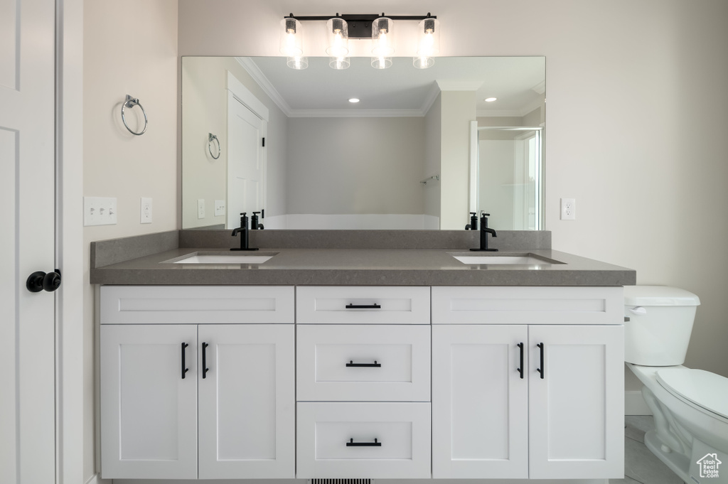 Full bathroom with crown molding, toilet, a stall shower, and double vanity