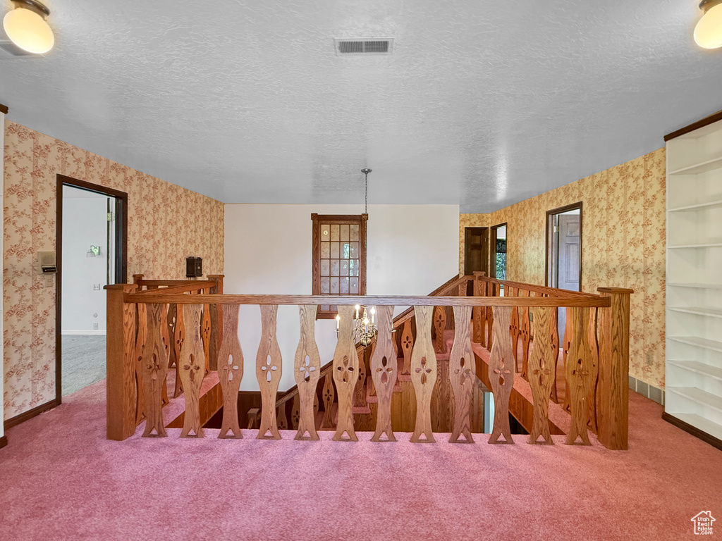 Staircase featuring wallpapered walls, carpet flooring, baseboards, and a textured ceiling