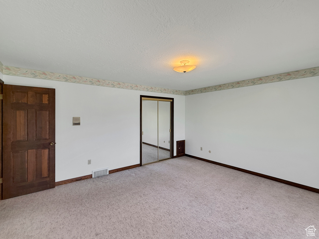 Unfurnished bedroom featuring carpet floors, baseboards, a closet, and a textured ceiling