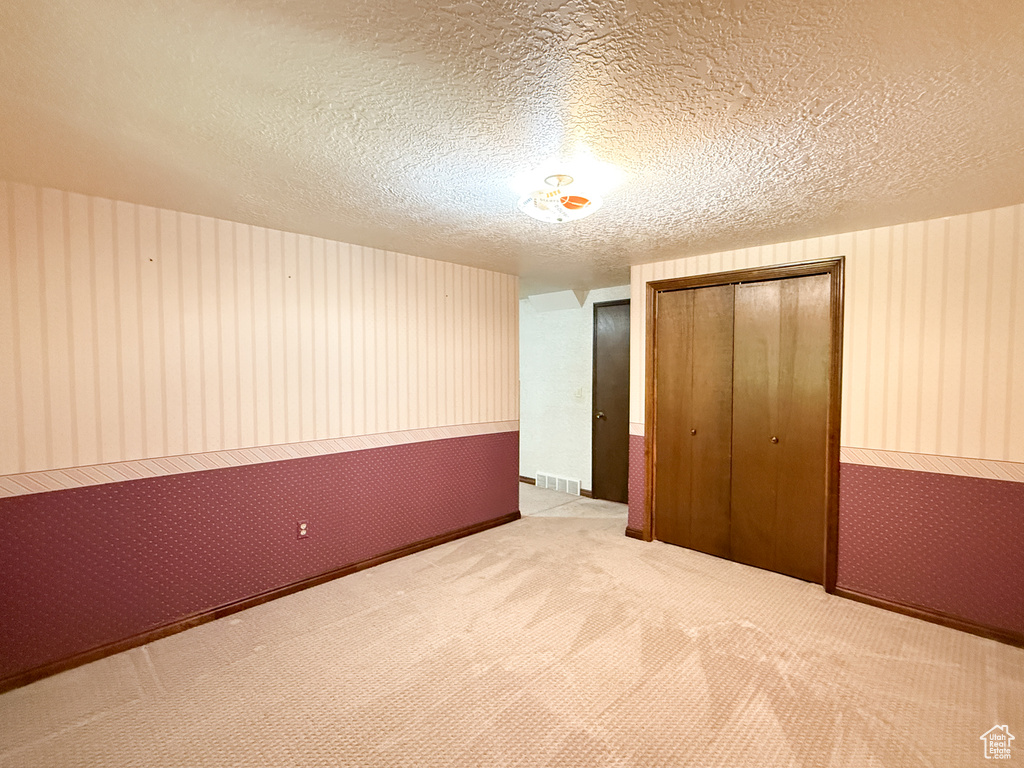 Unfurnished bedroom with a closet, carpet, and a textured ceiling