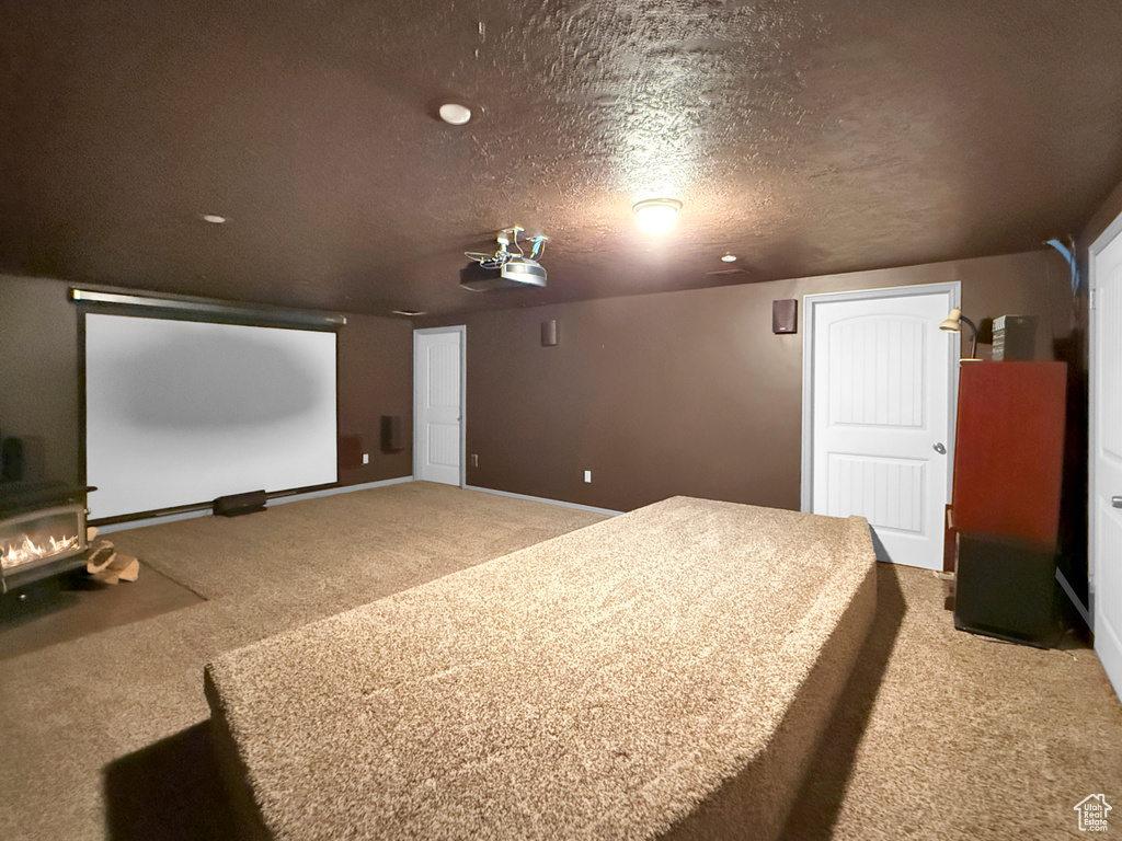 Carpeted home theater featuring a textured ceiling and baseboards