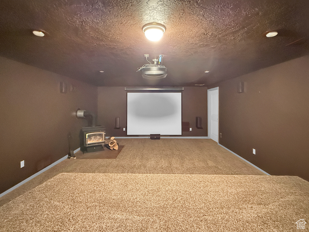 Cinema with carpet flooring, a wood stove, baseboards, a textured ceiling, and recessed lighting