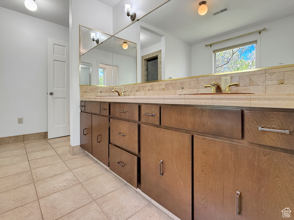 Bathroom with tile patterned floors, double vanity, and decorative backsplash