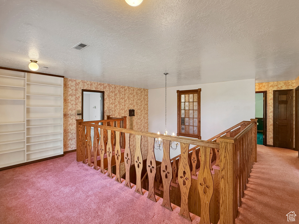 Staircase with carpet flooring, wallpapered walls, and a textured ceiling