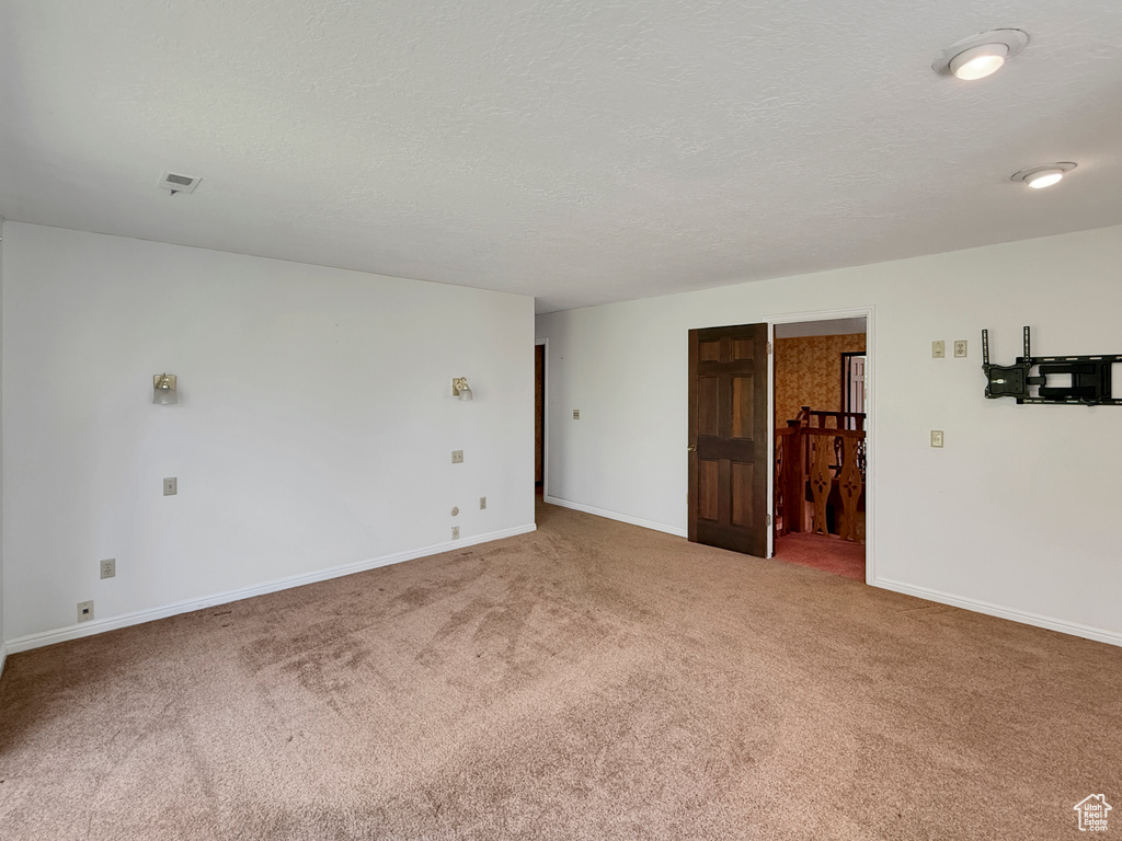 Carpeted spare room featuring a textured ceiling and baseboards