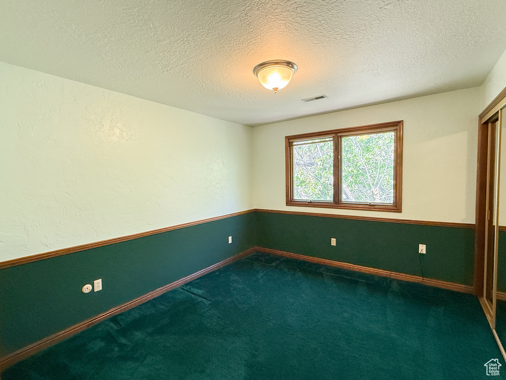 Unfurnished room with carpet, a textured ceiling, and baseboards