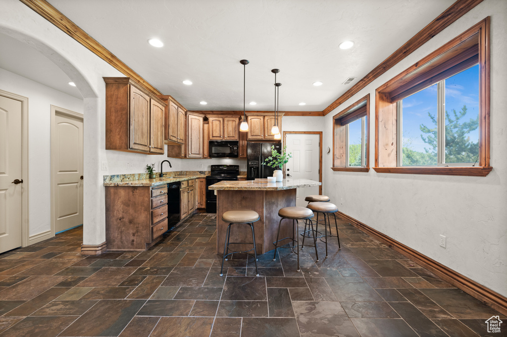 Kitchen with black appliances, baseboards, recessed lighting, a center island, and a breakfast bar