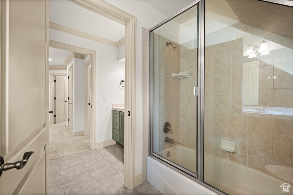 Bathroom with combined bath / shower with glass door, crown molding, vanity, tile patterned floors, and baseboards