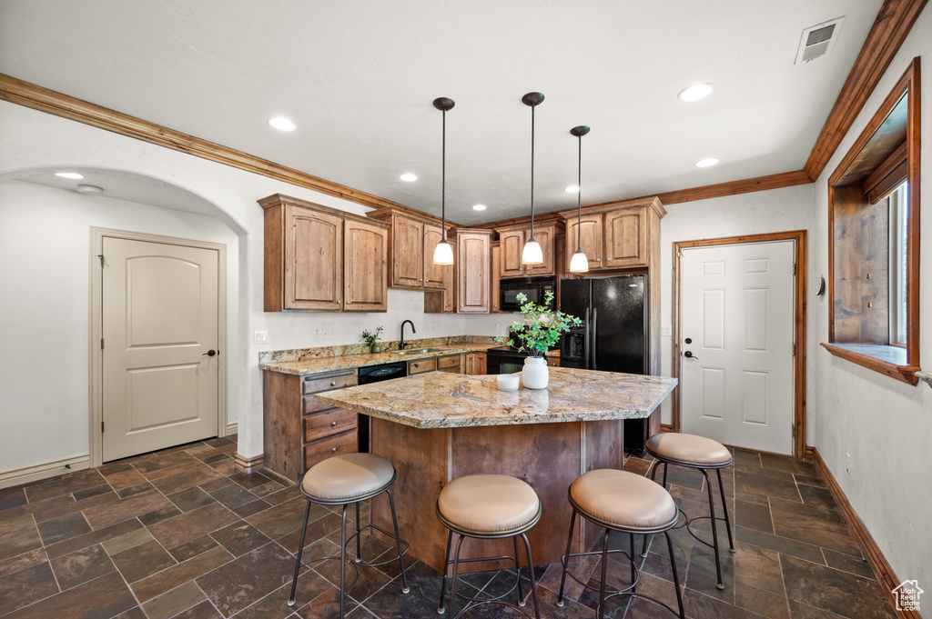 Kitchen with baseboards, a kitchen bar, black appliances, a sink, and crown molding